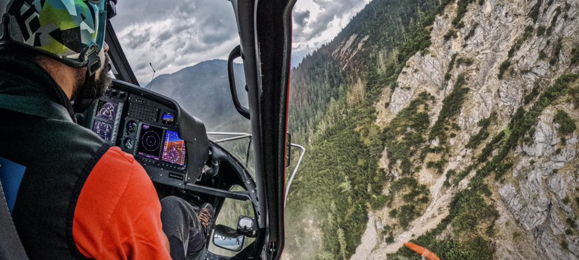 Blick auf einen Berg und den Rücken des Piloten aus der Perspektive eines Hubschrauber-Passagiers