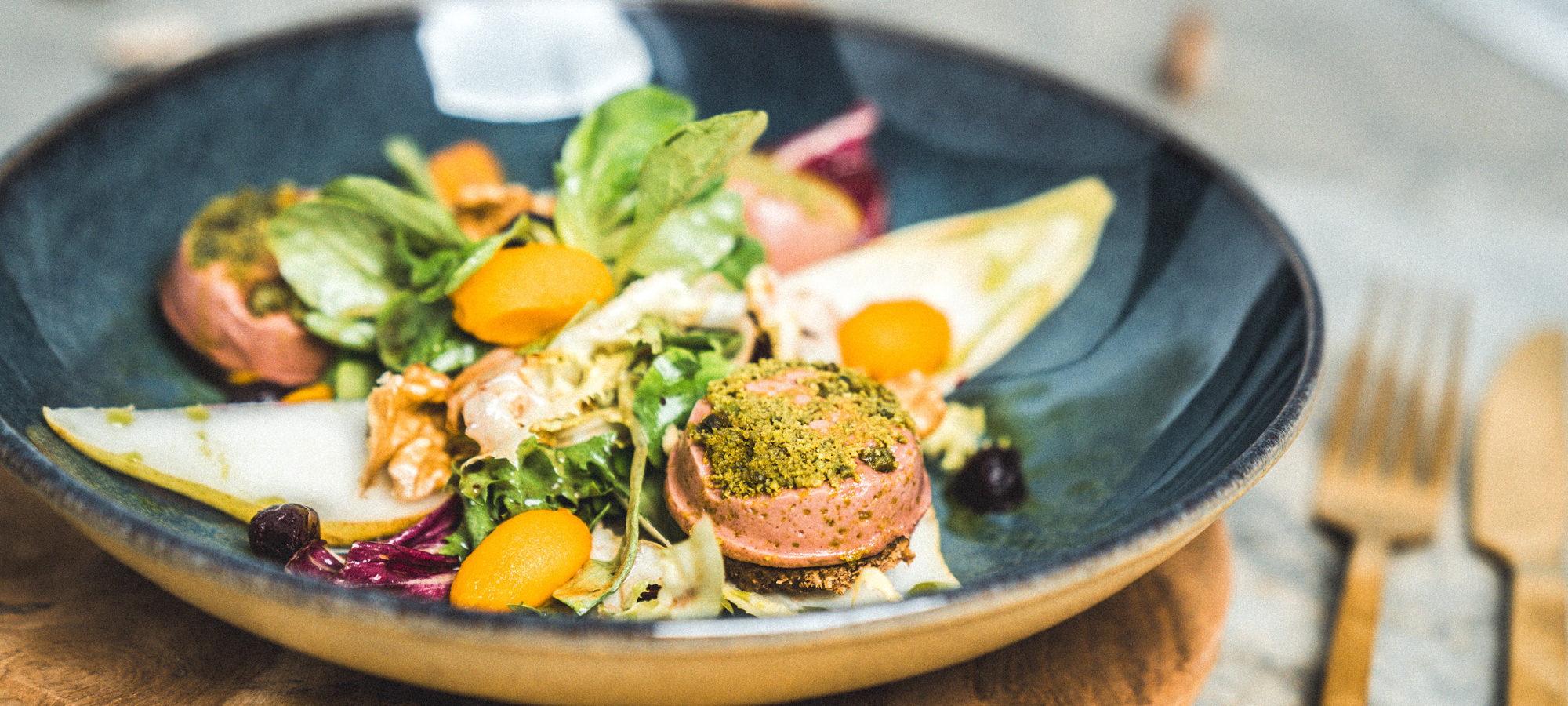 Kunstvoll angerichteter Salat aus Chicorée, Birne, Walnüssen und Maronen-Pinienkern-Paté mit Preiselbeerdressing